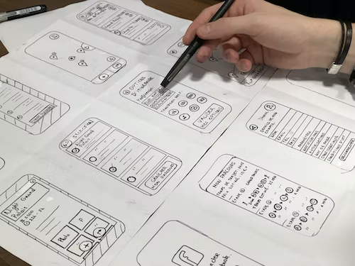 white paper sheet with hand-drawn UI/UX designs of mobile development