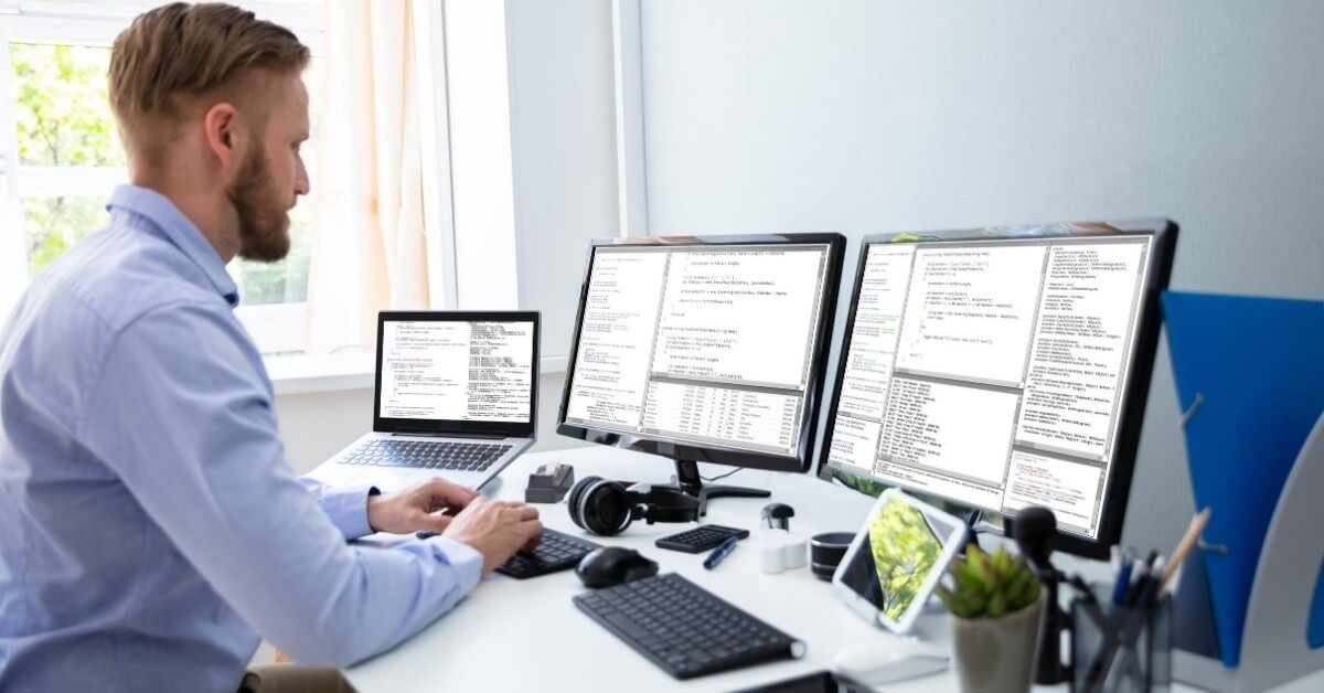 Outsourced software developer working from home on three screens