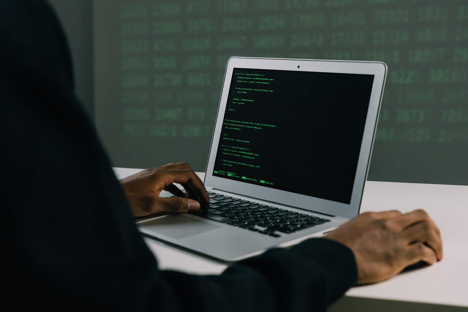 Man sitting in front of a computer with lime green code on the screen