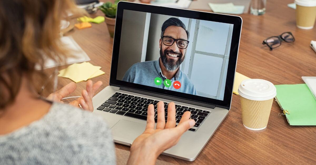 Woman chatting with a bearded man in video conference on her laptop