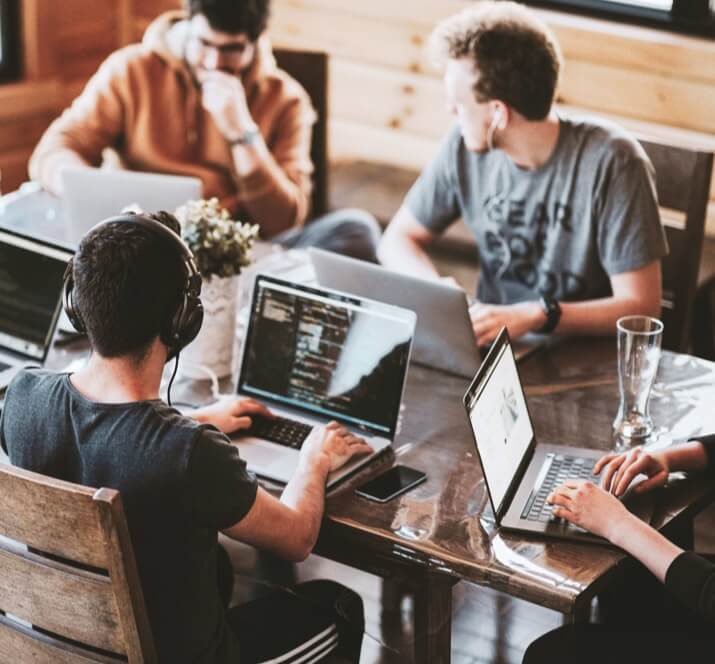 Software Development Outsourcing Company | Blue Coding Software Development Outsourcing Company (image showing nearshore software developers sitting at a large table working)